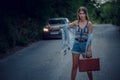 Pretty young woman hitchhiking along a road Royalty Free Stock Photo