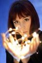 Pretty young woman holds a string of lights close to the camera Royalty Free Stock Photo