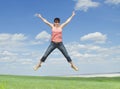 Young woman jumping on green grass over blue sky Royalty Free Stock Photo