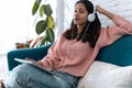 Pretty young woman listening to music with digital tablet and relaxing while sitting on sofa at home Royalty Free Stock Photo