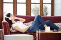 Pretty young woman listening to music while relaxing on couch at home Royalty Free Stock Photo