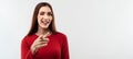 Smiling Young woman with long chestnut hair looking at the camera and pointing her finger at you. Copy space Royalty Free Stock Photo