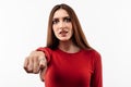 Pretty Young woman with long chestnut hair looking at the camera and pointing her finger at you. Human emotions concept Royalty Free Stock Photo