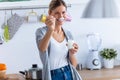 Pretty young woman looking at camera while eating yogurt in the kitchen at home Royalty Free Stock Photo