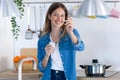 Pretty young woman looking at camera while eating yogurt in the kitchen at home Royalty Free Stock Photo