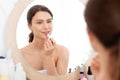 Pretty young woman using lipstick, looking at mirror Royalty Free Stock Photo