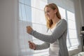 Pretty, young woman lowering the interior shades/blinds