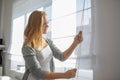 Pretty, young woman lowering the interior shades/blinds