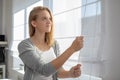 Pretty, young woman lowering the interior shades/blinds