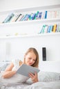 Pretty, young woman lying in bed, using her tablet computer Royalty Free Stock Photo