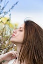 Pretty young woman near tree with flowers