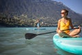 Pretty, young woman paddling on a paddle board on a lake