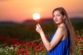 beautiful young woman playing with sun ball while standing in poppy field in warm sunset light Royalty Free Stock Photo