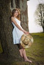 Pretty young woman posing in front of the farm. Very attractive blonde girl with white short dress holding a hat. Romantic girl Royalty Free Stock Photo