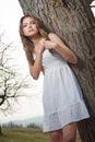 Pretty young woman posing laying on a tree. Very attractive blonde girl with white short outdoor on a hill. Romantic young woman Royalty Free Stock Photo