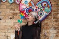 Pretty young woman in punk style holds a colourful windmill in her hand. She is blowing it to make it spin. Summer, air