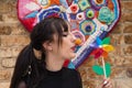 Pretty young woman in punk style holds a colourful windmill in her hand. She is blowing it to make it spin. Summer, air