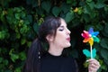 Pretty young woman in punk style holds a colourful windmill in her hand. She is blowing it to make it spin. Summer, air Royalty Free Stock Photo