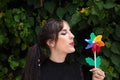 Pretty young woman in punk style holds a colourful windmill in her hand. She is blowing it to make it spin. Summer, air Royalty Free Stock Photo