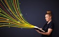 Pretty young woman reading a book while colorful lines are coming out of the book Royalty Free Stock Photo