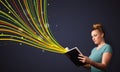 Pretty young woman reading a book while colorful lines are coming out of the book Royalty Free Stock Photo