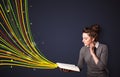 Pretty young woman reading a book while colorful lines are coming out of the book Royalty Free Stock Photo