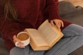 pretty young woman reading a book and drinking coffee happily, sitting on some stairs Royalty Free Stock Photo