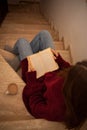 pretty young woman reading a book and drinking coffee happily, sitting on some stairs Royalty Free Stock Photo