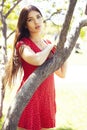 Pretty young woman in red dress smiling cheerful in green park at tree on summer sunny day, lifestyle people concept Royalty Free Stock Photo