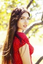 Pretty young woman in red dress smiling cheerful in green park at tree on summer sunny day, lifestyle people concept Royalty Free Stock Photo