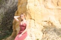 pretty young woman in red summer dress is posing on the cliff. The woman makes different body expressions. In the background rocks Royalty Free Stock Photo