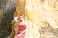 pretty young woman in red summer dress is posing on the cliff. The woman makes different body expressions. In the background rocks Royalty Free Stock Photo