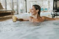 Young woman relaxing in the indoor swimming pool with glass of fresh orange juice Royalty Free Stock Photo