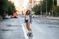 Pretty woman riding on a skateboard on an empty city road early in morning Royalty Free Stock Photo