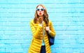 Pretty young woman sends an air kiss on blue background