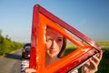 Pretty, young woman setting the safety triangle on the roadside