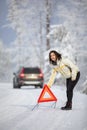 Pretty, young woman setting up a warning triangle and calling for assistance