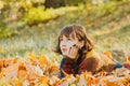 Pretty young woman with short wavy brunette hair lying at ground covered with fallen orange leaves. Magic beautiful Royalty Free Stock Photo