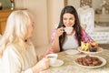 Pretty woman drinks tea with her senior mother at cafe. Royalty Free Stock Photo