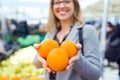 Pretty young woman showing oranges to camera in the street market. Royalty Free Stock Photo