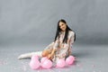 A pretty young woman sits near pink balloons and confetti on a gray studio backdrop Royalty Free Stock Photo