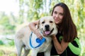 Pretty young woman sitting and hugging her dog at river bank in summer park Royalty Free Stock Photo