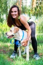 Pretty young woman sitting and hugging her dog at river bank in summer park Royalty Free Stock Photo