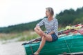 Pretty young woman sitting on wooden boat on the beach contemplating sea coast Outdoors summertime close-up horizontal colored