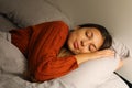 Pretty young woman sleeps hugging pillow on bed at night