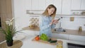 Stylish girl uses mobile and holds mug of tea in hands, standing Royalty Free Stock Photo