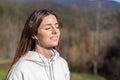 Pretty young woman smiling breathes fresh air in the park listening to music on headphones