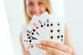 Pretty young woman smiling and holding poker cards at home.