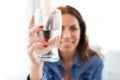 Pretty young woman smiling while looking at the camera through the glass of water at home Royalty Free Stock Photo