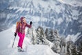 Pretty, young woman snowshoeing in high mountains